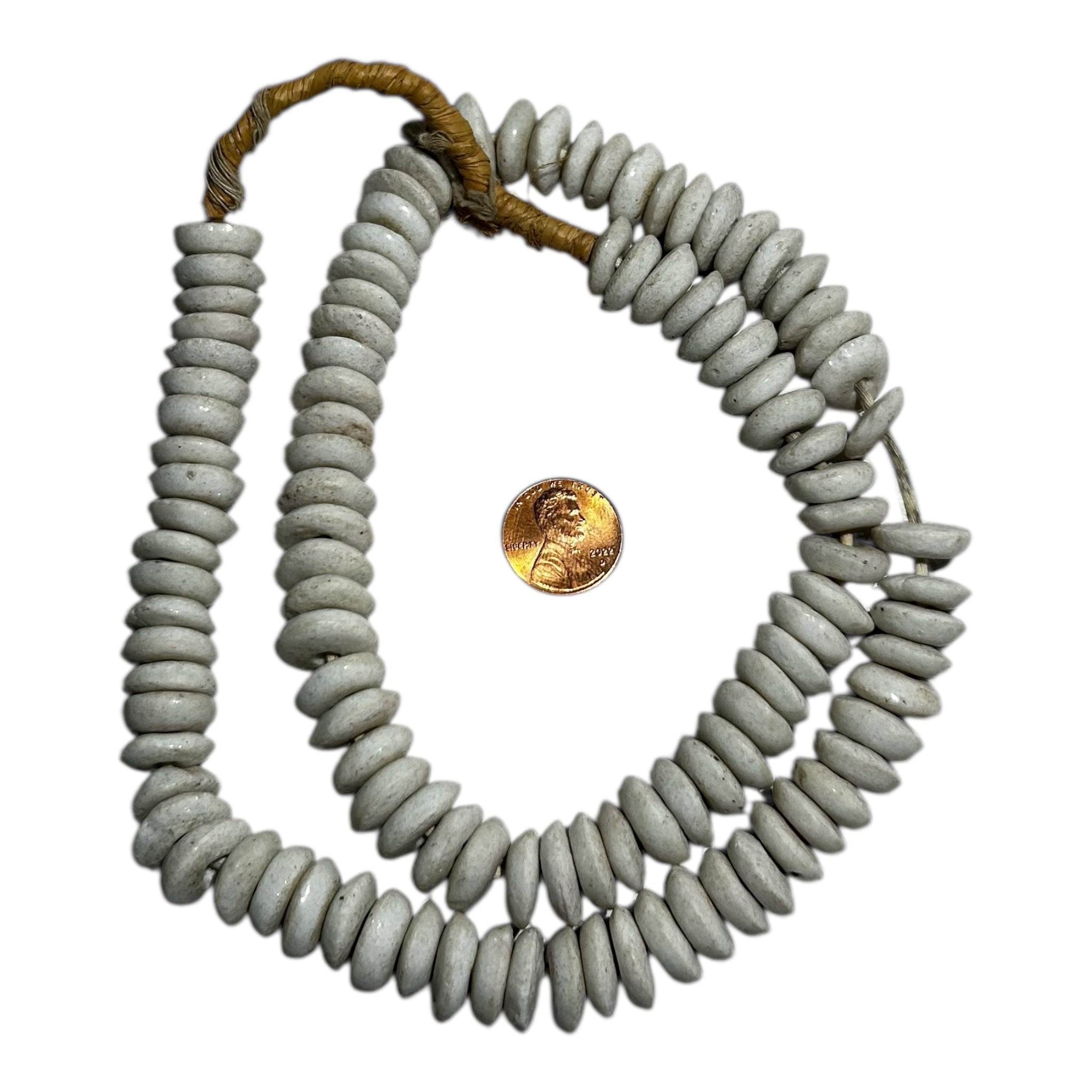 Necklace with gray beads and a brown cord, next to a gold coin for scale.