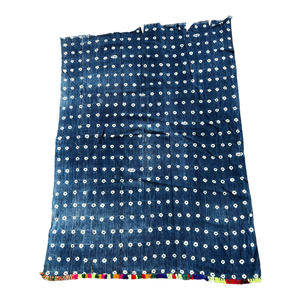 Blue fabric with white patterns and colorful trim on a white background