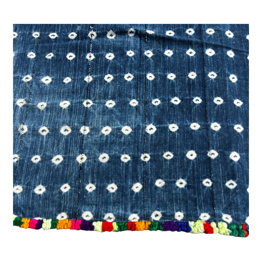 Blue fabric with white floral patterns and colorful trim on a white background