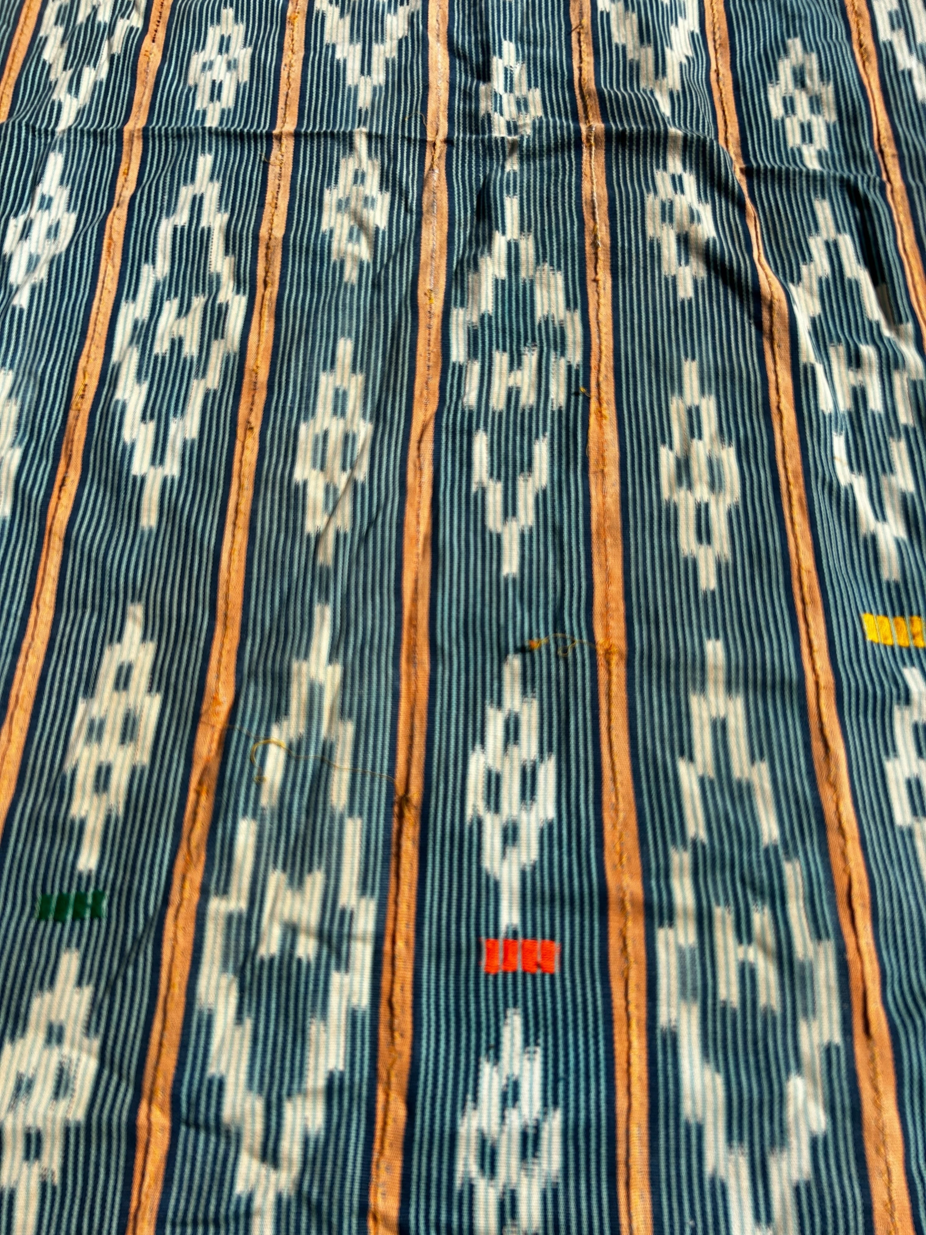 Close-up of fabric with a geometric pattern featuring blue, orange, and white colors.